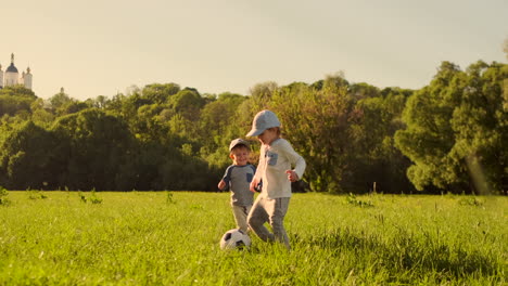 Two-boys-play-with-a-soccer-ball-laughing-and-smiling-at-sunset-in-the-field.